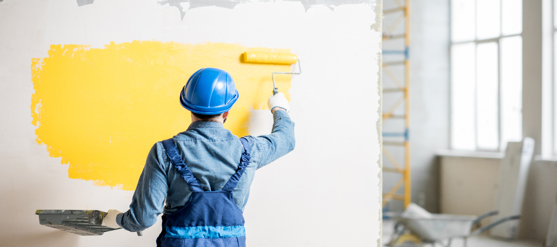 Male painting a wall in an empty business space